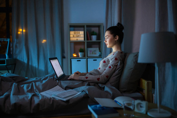 teenage girl with laptop learning in bed at night - Φωτογραφία, εικόνα