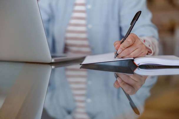 Mulher usando laptop e escrevendo em notebook em casa - Foto, Imagem