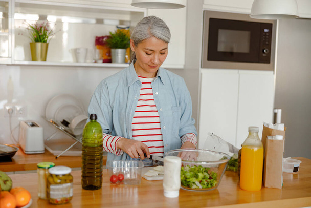 Donna che fa insalata in cucina a casa - Foto, immagini