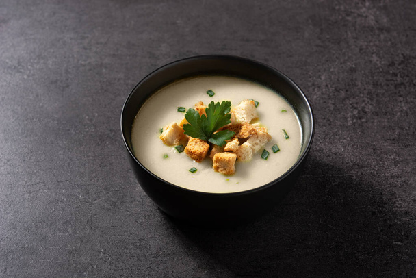 Garlic soup topped with croutons in bowl on black slate background - Foto, imagen