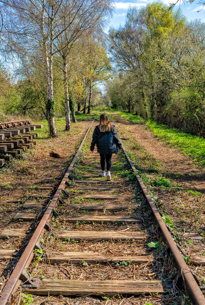 イギリスの廃線に沿って距離を歩く若い女の子 - 写真・画像