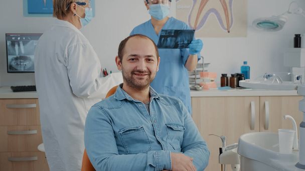 Portret van een patiënt in een tandartsstoel in een kliniek voor mondverzorging - Foto, afbeelding