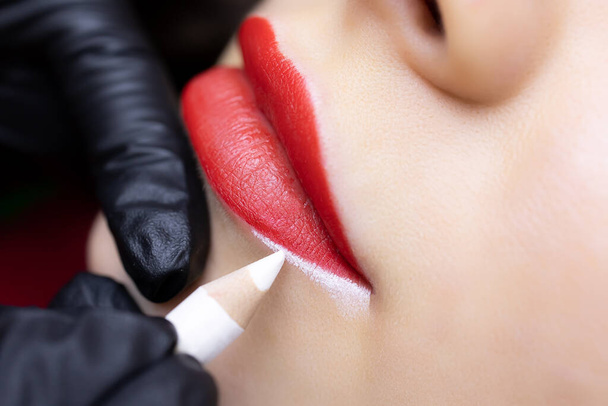 procedimiento de tatuaje labial permanente primer plano de la preparación de los labios del modelo para el procedimiento de tatuaje delineado contornos con un lápiz blanco - Foto, Imagen