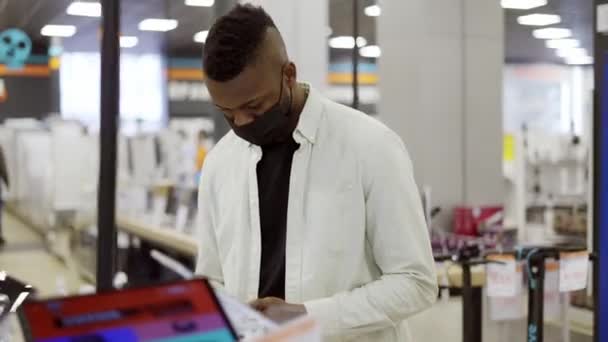 Afro-Amerikaanse man kiest een nieuwe mobiele telefoon in een winkel, om te controleren hoe het werkt - Video