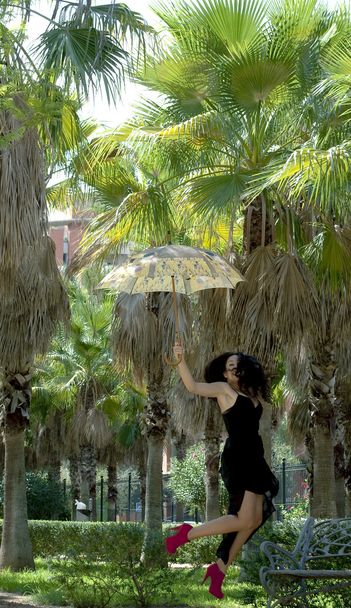 Bella donna che salta in un parco con ombrellone
  - Foto, immagini