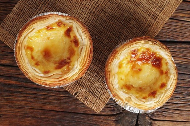 Freshly baked egg tarts (pastel de nata) on wooden background, top view - Photo, Image