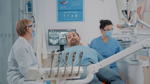 Estomatólogo y enfermera terminan procedimiento de cuidado oral con paciente - Foto, imagen