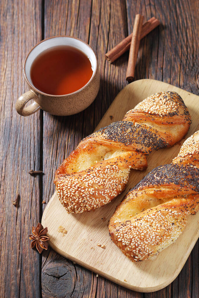 Tasse de thé chaud avec de délicieux petits pains avec des graines sur fond en bois, vue sur le dessus - Photo, image