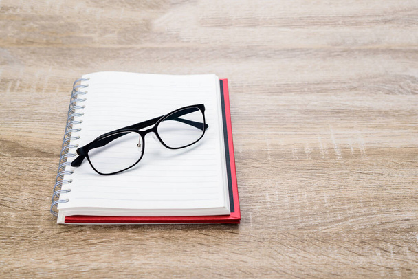 Konzept Bildung oder Business: Tagebuch oder Notizbuch mit schwarzer Brille auf Holztisch aufschlagen. - Foto, Bild