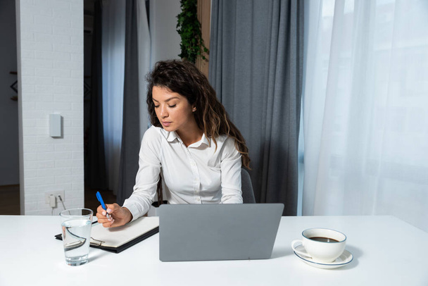 Young happy successful business woman sitting in office working on laptop computer and enjoying the work she love. Businessperson remotely freelancing working at home on new project for company.  - Φωτογραφία, εικόνα