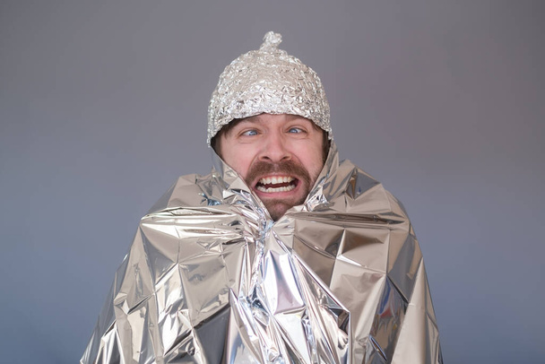 Jeune homme dans une casquette de papier d'aluminium ayant peur et stressé. Peur des radiations ou des étrangers - Photo, image