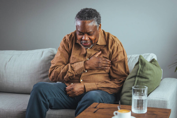 Senior man who suffers, shrinks and has difficulty breathing, chest pain or heart attack during the corona virus pandemic crisis, life insurance. Heart attack symptoms. Senior health care concepts - Photo, image