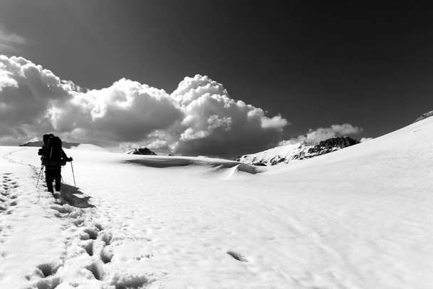 Two hikers on snowy plateau. Turkey, Central Taurus Mountains, Aladaglar (Anti-Taurus), plateau Edigel (Yedi Goller). Wide angle view. Black and white toned landscape - 写真・画像
