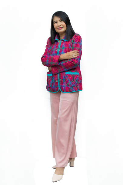 На белом фоне портрет уверенной в себе азиатки средних лет в розовой повседневной одежде скрещивает руки. - Фото, изображение