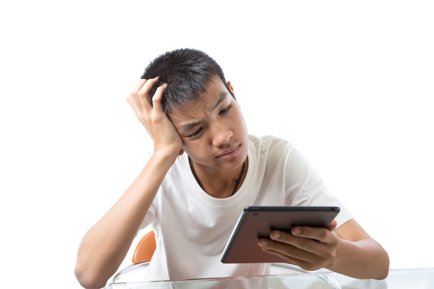 Asian teenager using his tablet or ipad and thinking hard - Foto, immagini