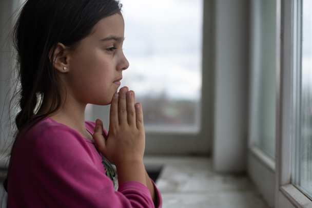 Маленькая девочка молится на белом столе утром. Рука девочки молится, руки сложены в молитвенной концепции веры, духовности и религии. - Фото, изображение