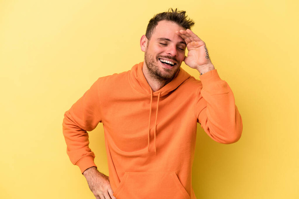 Young caucasian man isolated on yellow background joyful laughing a lot. Happiness concept. - Photo, Image