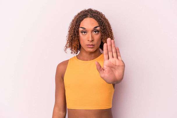 Junge lateinamerikanische transsexuelle Frau isoliert auf rosa Hintergrund stehend mit ausgestreckter Hand zeigt Stoppschild, verhindert, dass Sie. - Foto, Bild