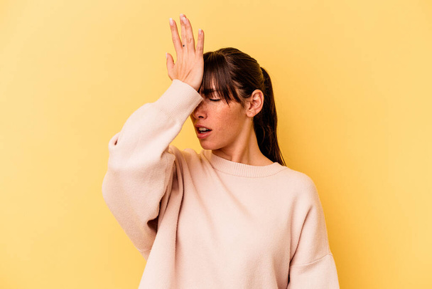 Young Argentinian woman isolated on yellow background forgetting something, slapping forehead with palm and closing eyes. - Foto, imagen
