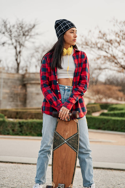 Mulher hipster bonita posando com skate. Mulher latina hispânica vestindo roupas casuais. - Foto, Imagem