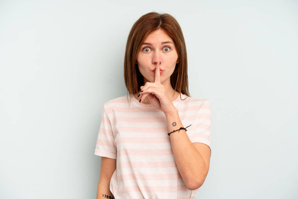 Jonge Engelse vrouw geïsoleerd op blauwe achtergrond houden van een geheim of vragen om stilte. - Foto, afbeelding