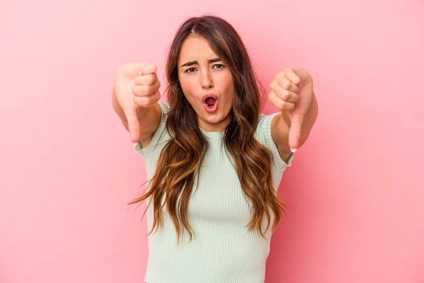 Young caucasian woman isolated on pink background showing thumb down and expressing dislike. - Photo, Image