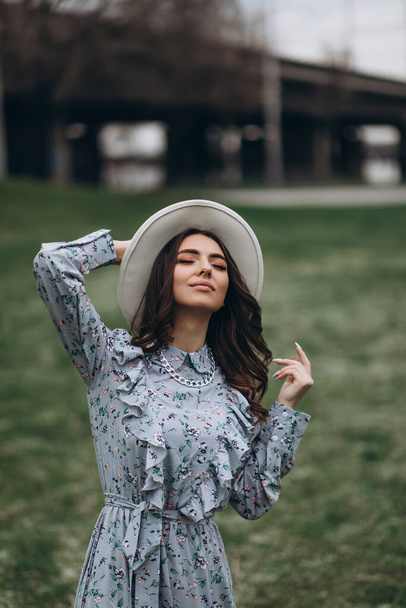 beautiful young woman in a hat and dress on the background of a field with flowers. spring - Fotografie, Obrázek