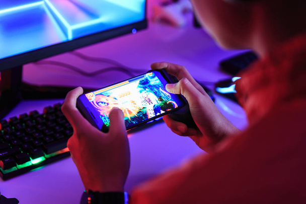 Gamer jugar juego en línea en el teléfono inteligente en la habitación oscura. Recopilación e-Sport Games y Campeonato de Internet. - Foto, imagen