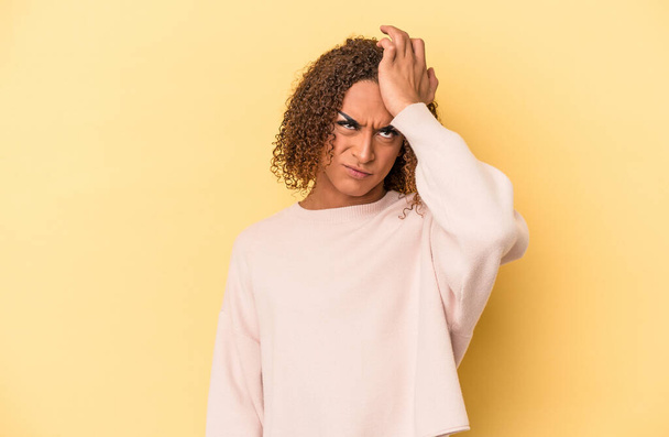 Jonge latijn transseksuele vrouw geïsoleerd op gele achtergrond vergeten iets, klap voorhoofd met palm en het sluiten van de ogen. - Foto, afbeelding