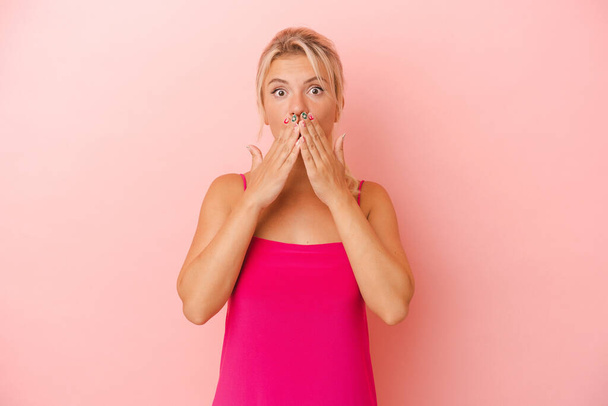 Νεαρή ρωσίδα γυναίκα απομονωμένη σε ροζ φόντο σοκαρισμένη κάλυψη στόμα με τα χέρια. - Φωτογραφία, εικόνα