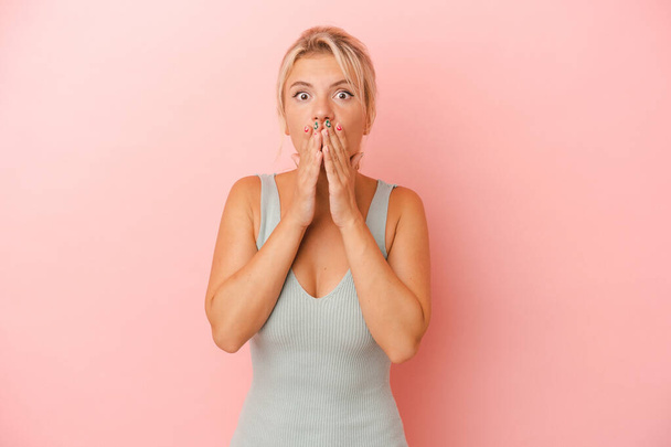 Young Russian woman isolated on pink background covering mouth with hands looking worried. - Photo, Image