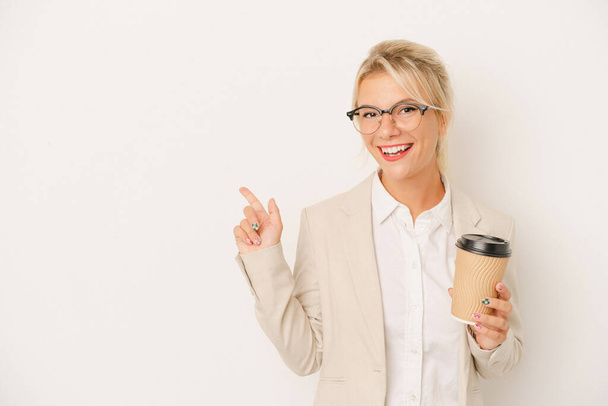 Joven mujer rusa de negocios sosteniendo tomar café aislado sobre fondo blanco sonriendo y señalando a un lado, mostrando algo en espacio en blanco. - Foto, imagen