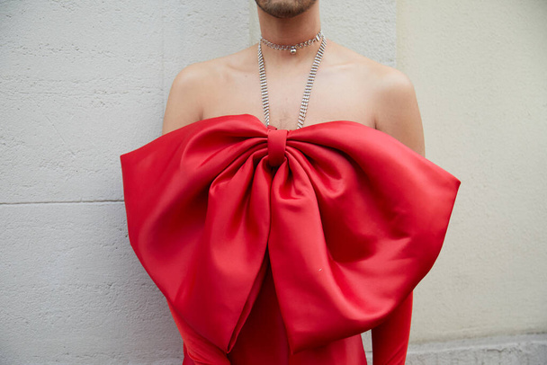 MILÁN, ITALIA - 24 DE FEBRERO DE 2022: Hombre con un gran collar de cinta roja antes del desfile de moda Genny, Milan Fashion Week street style - Foto, Imagen