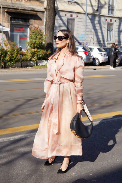 MILAN, ITALY - FEBRUARY 23, 2022: Woman with pink silk trench coat  and black leather Fendi bag before Fendi fashion show, Milan Fashion Week street style - Zdjęcie, obraz