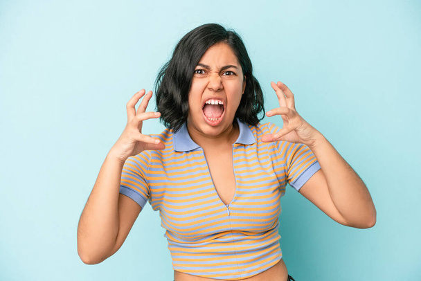 Young latin woman isolated on blue background screaming with rage. - Photo, Image