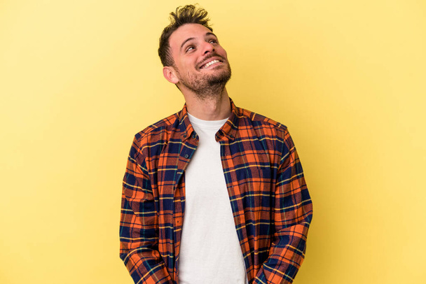 Jonge blanke man geïsoleerd op gele achtergrond ontspannen en gelukkig lachen, nek gestrekt tonen tanden. - Foto, afbeelding