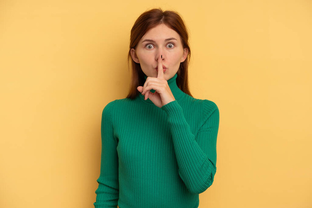 Young English woman isolated on yellow background keeping a secret or asking for silence. - Foto, imagen