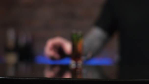 De barman is een jonge man de man schenkt drankjes in, maakt alcoholische shots zwart inktvis in de bar - Video