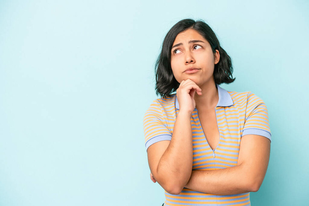 Young latin woman isolated on blue background looking sideways with doubtful and skeptical expression. - Foto, Bild