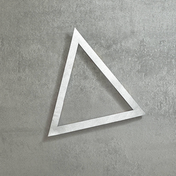 Semplice cornice triangolare in argento su sfondo grigio cemento. Spazio di testo. Vista dall'alto. Stile minimale. - Foto, immagini