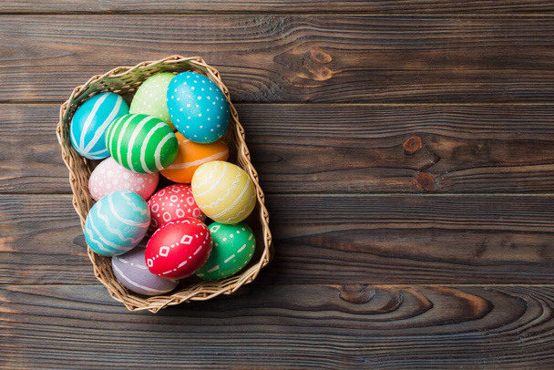 Huevos de Pascua multicolores en la cesta tejida sobre fondo de color. Huevos de Pascua color pastel. concepto de vacaciones con espacio de copia. - Foto, imagen