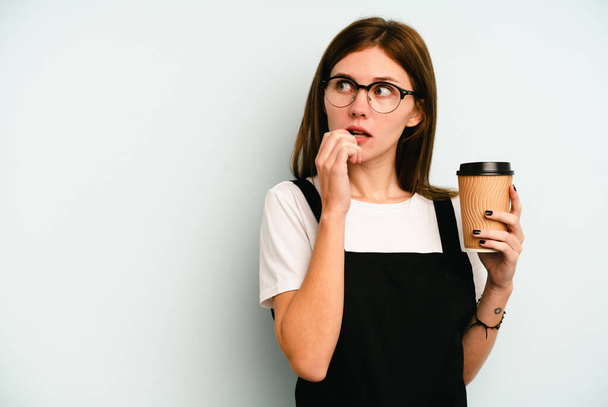 Ristorante cameriera donna in possesso di un caffè da asporto isolato su sfondo blu rilassato pensando a qualcosa guardando uno spazio copia. - Foto, immagini