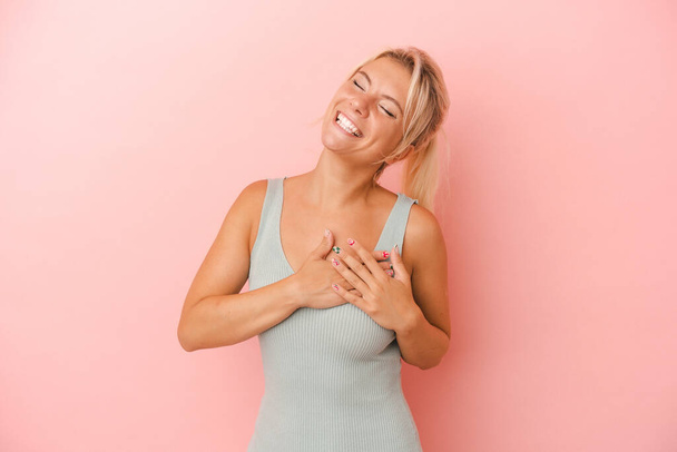 Νεαρή Ρωσίδα απομονωμένη σε ροζ φόντο γελώντας κρατώντας τα χέρια στην καρδιά, έννοια της ευτυχίας. - Φωτογραφία, εικόνα