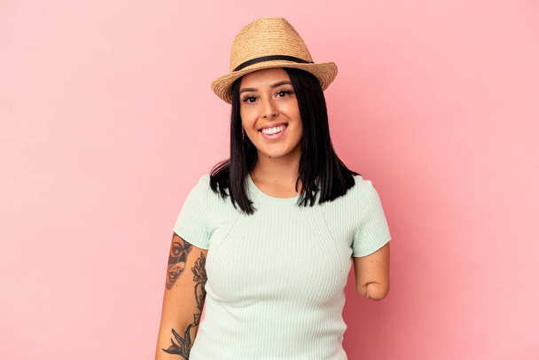 Young caucasian woman with one arm wearing a summer hat isolated on pink background happy, smiling and cheerful. - Photo, Image