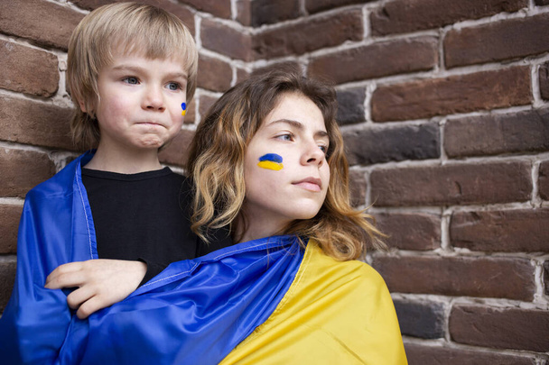 niño y una mujer joven con una bandera de Ucrania amarillo-azul. Familia, unidad, apoyo. Los ucranianos están en contra de la guerra. pidiendo ayuda a la comunidad mundial. de pie con Ucrania - Foto, imagen