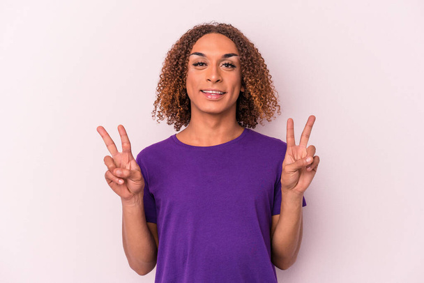Young latin transsexual woman isolated on pink background showing victory sign and smiling broadly. - Photo, Image