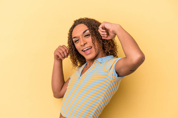 Joven transexual latina aislada sobre fondo amarillo celebrando un día especial, salta y levanta los brazos con energía. - Foto, imagen