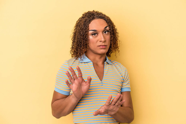 Fiatal latin transzszexuális nő elszigetelt sárga háttér elutasítja valaki mutató gesztusa undor. - Fotó, kép