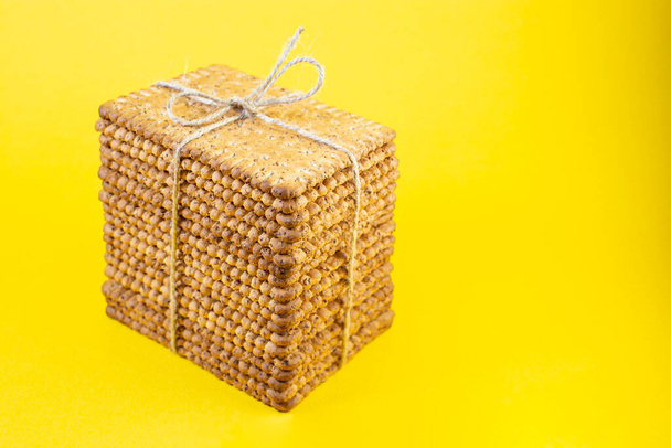 staked biscuits present, tied with jute rope bow and isolated on yellow - Photo, Image