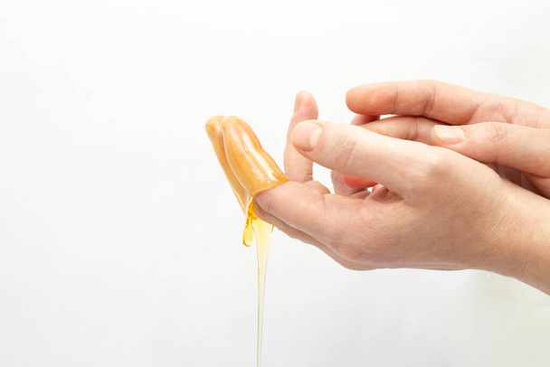 Woman's hands applying dripping honey on dried skin - Photo, Image